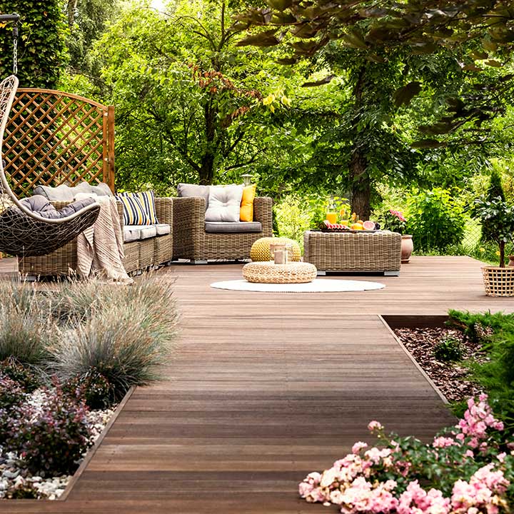 Holzterrasse mit Loungemöbeln und Hängesessel im Garten